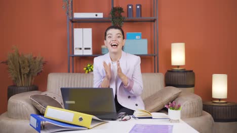 Home-office-worker-young-woman-looking-at-camera-clapping-and-getting-excited.